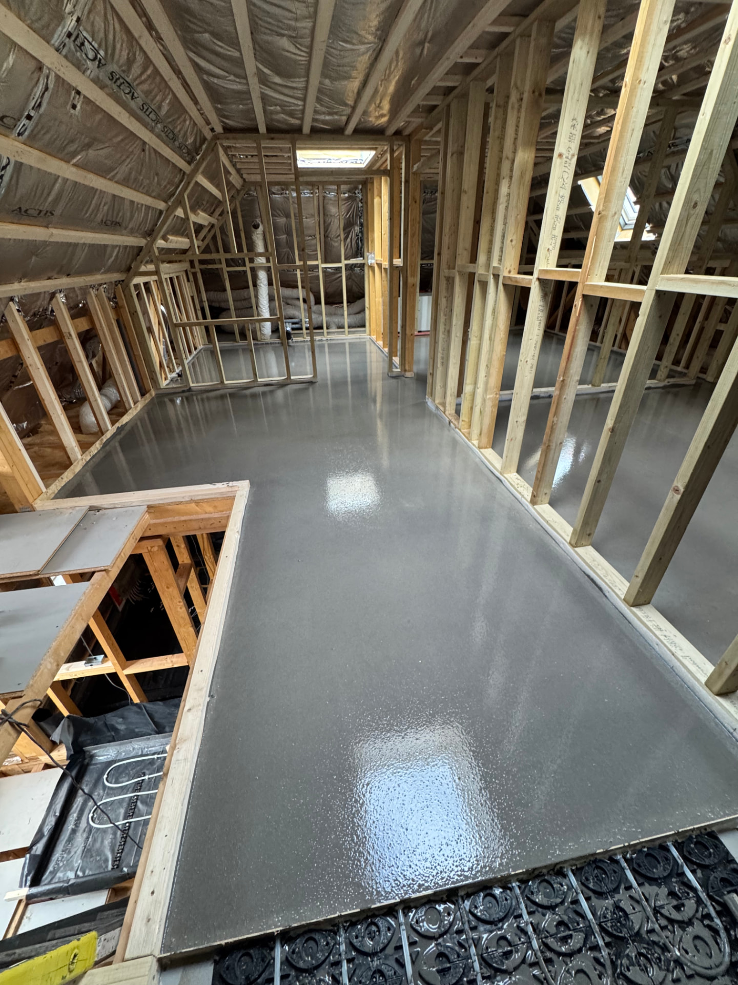 Fresh liquid screed poured over underfloor heating in a timber-framed loft