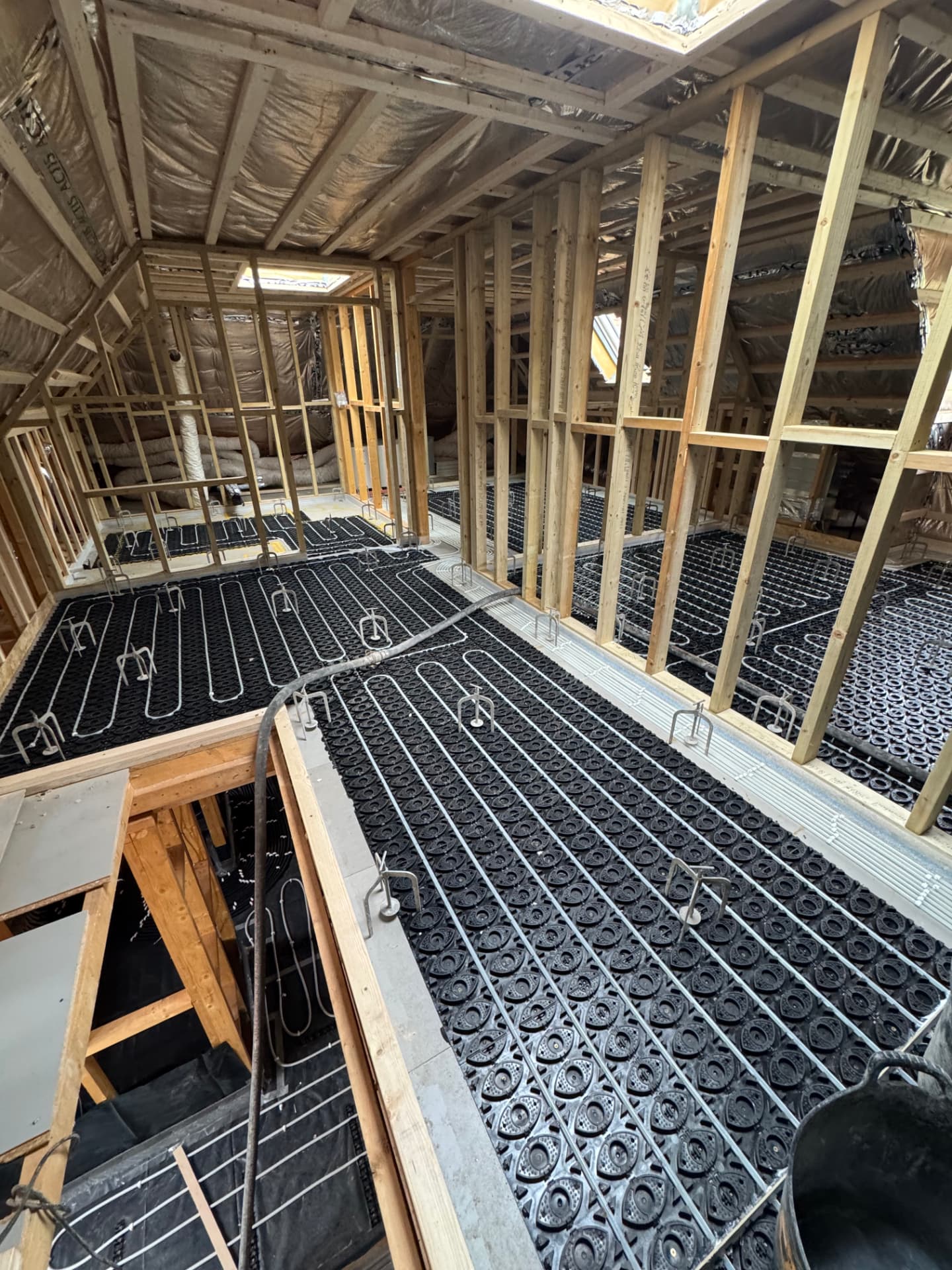 Underfloor heating pipework installed throughout a timber-framed loft